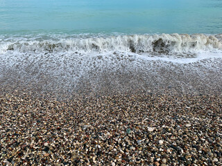Sea pebbles background, sea wave on the pebbly coast