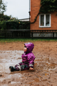 Toddler girl sitting in puddle