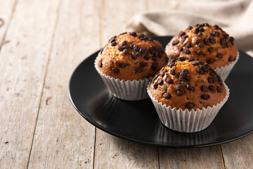 Just baked chocolate muffins on rustic wooden table