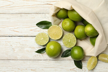 Bag with ripe lime on wooden background, space for text