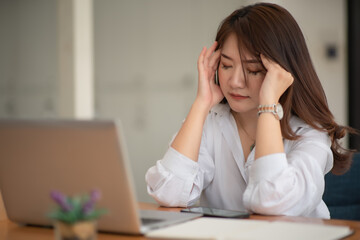 Asian businesswoman gets stressed while having a problem at work in the office.