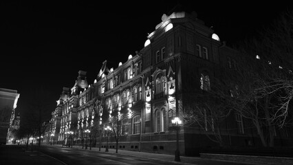 Obraz premium The facade of an old house at night. Street lights. Urban architecture with artificial lighting 