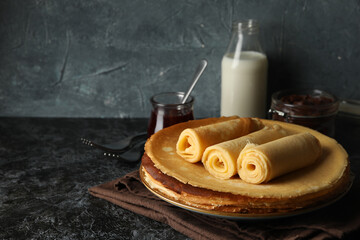 Concept of breakfast with crepes rolls on black smokey table