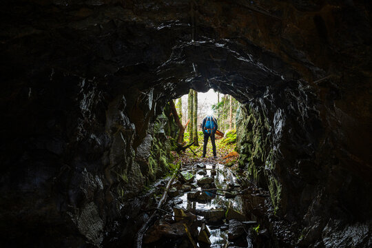 Spelunker with headlamp standing at cave entrance