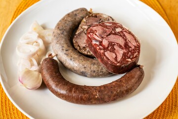 Bright and black pudding, sausage and onion on plate.