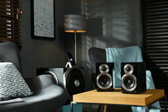 Modern audio speaker system on wooden table in living room
