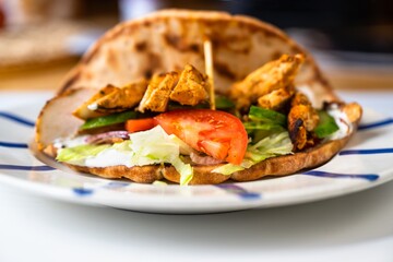 Chicken pieces in pita bread with vegetable salad( shawarma) on plate.