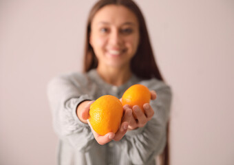 Woman with fresh tangerines on beige background, focus on fruits