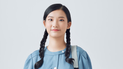 Young woman wearing a backpack ready to go to class, over white background