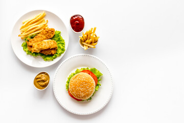 Burger with fried potatoes and chicken, top view