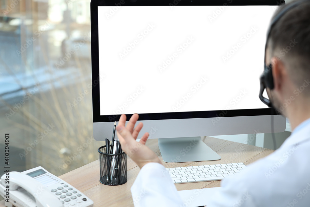 Poster Doctor with headset consulting patient online at desk in clinic, space for text. Health service hotline