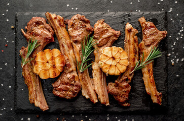 Grilled lamb ribs with spices and garlic on a stone background