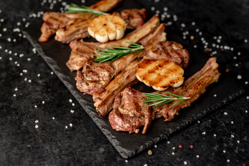 Grilled lamb ribs with spices and garlic on a stone background