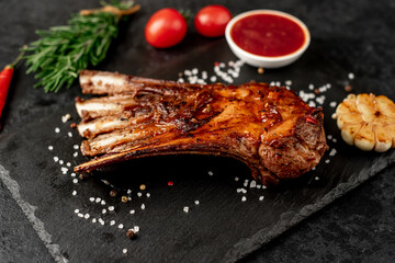 Grilled lamb ribs with spices and garlic on a stone background