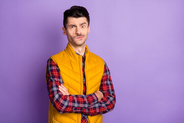 Photo of doubtful unsure young man wear yellow sleeveless jacket arms folded isolated violet color background