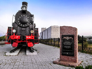 Buryn, Ukraine - August 18, 2018: An old steam locomotive and a memorial plate to the partisan railroad workers at the Putyvl Railway Station in Buryn (Sumy region). Outdoor World War II Monuments