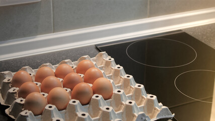 Eggs in  paper tray placed on pantry, Electric stove with blurred background in, Kitchen room, Preparing healthy food in morning with copy space.