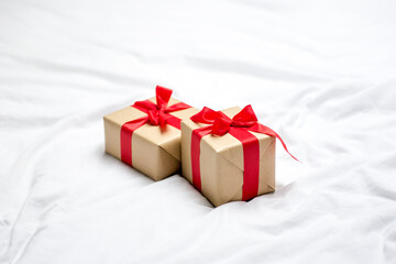 Red gift kraft box with ribbon. Valentine's Day gift in bed. Natural eco and bio gift. Sensual passion minimal gift in bed
