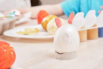 process of painting eggs for easter, eggs box, easter eggs, plate, brushes and paints on the table