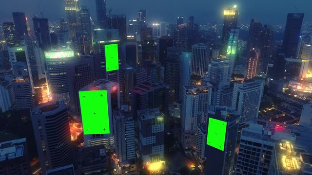 AERIAL. Top view of skyscrapers and green screen build board with tracking point. Bird view of modern city at night streets.