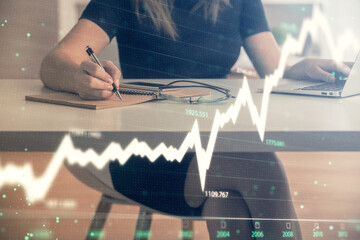 Double exposure of businesswoman hands typing on computer and forex chart hologram drawing....