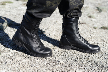 Man in black army boots with laces and khaki pants