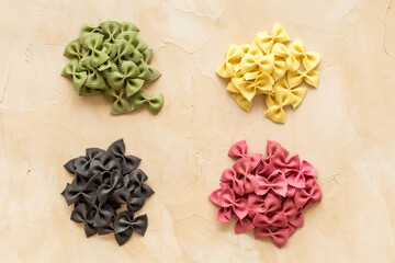 Fototapeta na wymiar Heaps of pasta - various colors farfalle pasta, top view