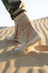 Tourist stands in the desert in beige pants and khaki boots