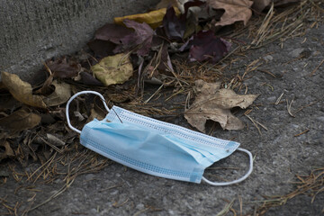 Closeup of a protective face mask with dry autumn leaves on the ground