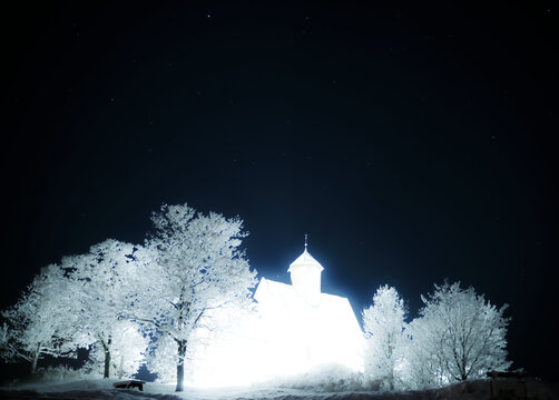 Medieval church of light, overexposed night photography of a Christian church on a hill.