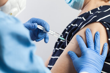 Nurse giving COVID-19 vaccine shot to elderly volunteer patient