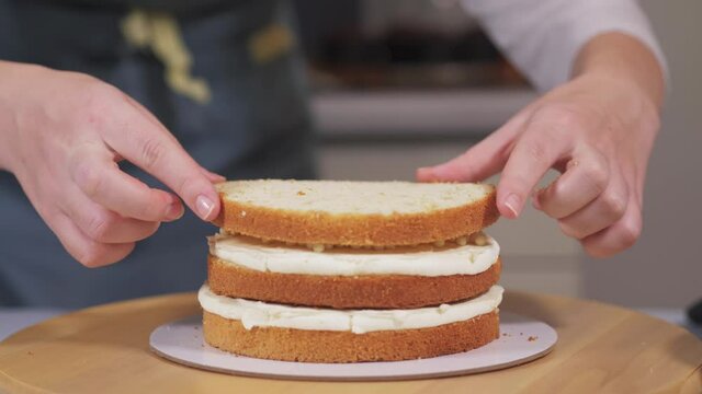 The pastry chef collects a cake from sponge cakes. The pastry chef puts the third layer of sponge cake. High quality 4k footage