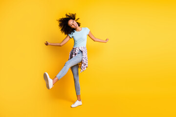 Fototapeta na wymiar Full length photo of charming dark skin wavy lady wear blue t-shirt dancing empty space isolated yellow color background