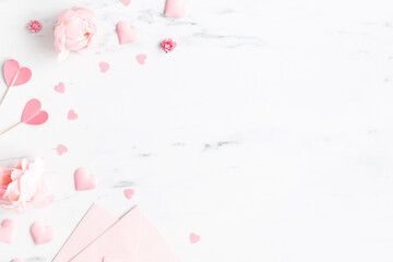Valentine's Day background. Pink flowers, envelope, hearts on marble background. Valentines day concept. Flat lay, top view