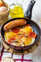 Fried egg with mushrooms, tomatoes in the pan.