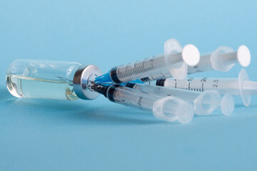 An ampoule of medicine and five disposable medical syringes stuck in the bottle cap, close-up on a...