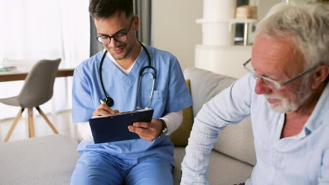 Male nurse talking to senior man while being in a home visit.