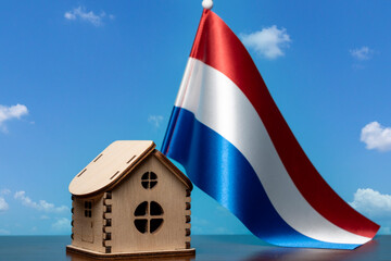 Small wooden house and Netherlands flag, sky on background. Real estate concept, copy space