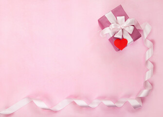Pink gift box, white bow, long curved ribbon, paper red heart and empty space for text. Top view, flat lay. Valentines Day, Wedding day, birthday, Mothers Day greeting background or invitation