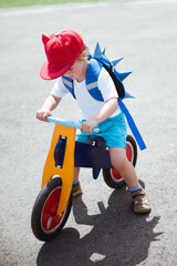 Adorable kid boy in red hat ride balance bike (run bike)