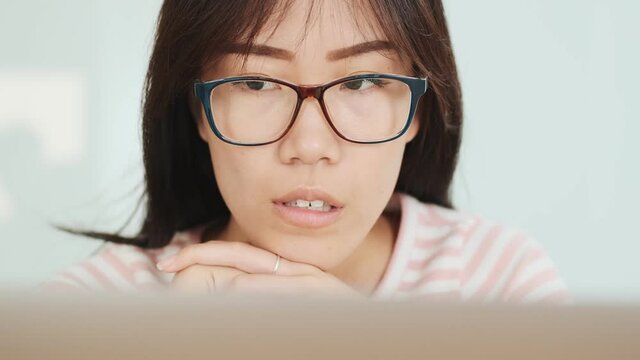 A close-up view of a serious asian woman is using laptop computer in the office