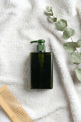 Natural organic SPA cosmetic product with eucalyptus leaf. Top view herbal hair care shampoo on white towel in bathroom.