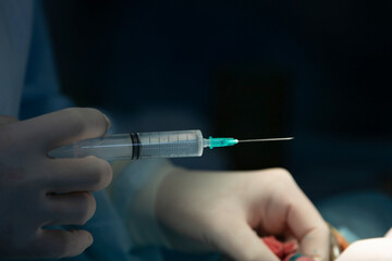 Surgeon holds syringe with transparent medicine close-up