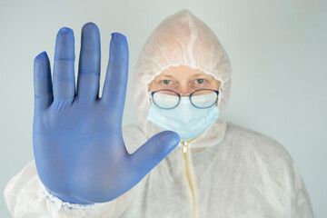 doctor in a protective decontamination suit held out a gloved hand to the gesturing stop