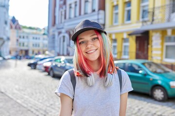 Portrait of fashionable smiling hipster teenage girl with colored dyed hair in black cap