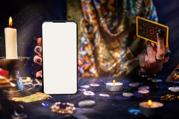 The fortune teller is holding a Tarot card and a smartphone with a white screen. Magic aura. Mock...