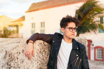 Serious young man contemplating standing against a city