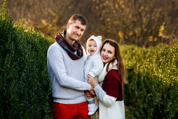 Young parents with a baby in their arms in the park. Portrait of a happy family.