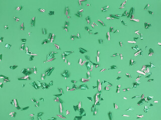 Confetti foil pieces on green background. Abstract festive backdrop.