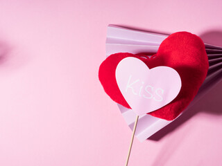 Trendy Valentines day backgound with stuffed red heart and purple paper fan on pink. Love concept with photo booth prop